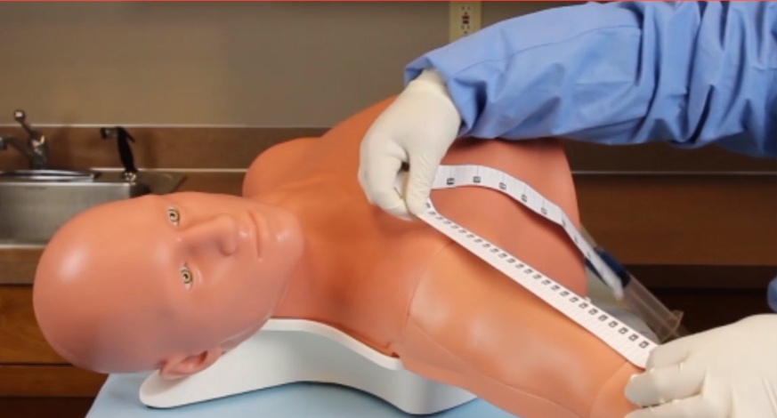 Caregiver measuring arm of training mannequin