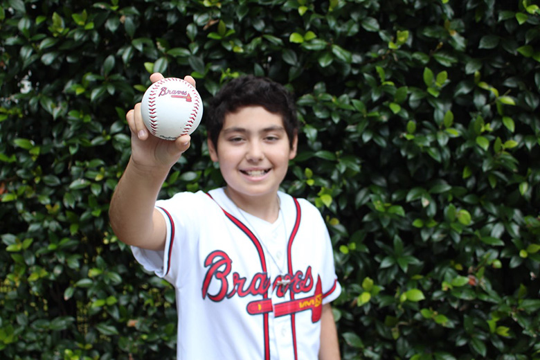 Aflac patient Jaxx holding a Braves baseball.